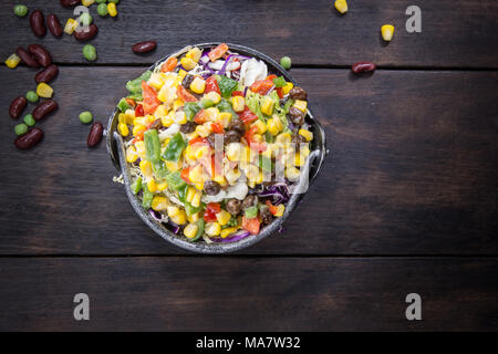 Insalata fresca con mais e miscelati su sfondo di legno vista dall'alto. Cibo sano. Foto Stock