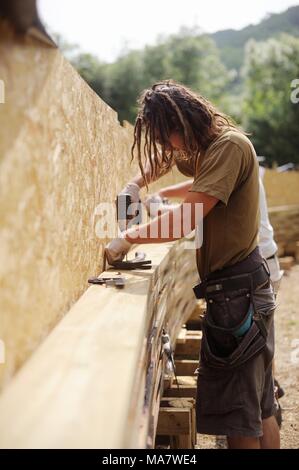4 in una serie di 32, la costruzione di una passerella di legno. Lavoratori offset fix di strati di legno con colla e viti nella forma ad arco Costruzione di un SCR Foto Stock