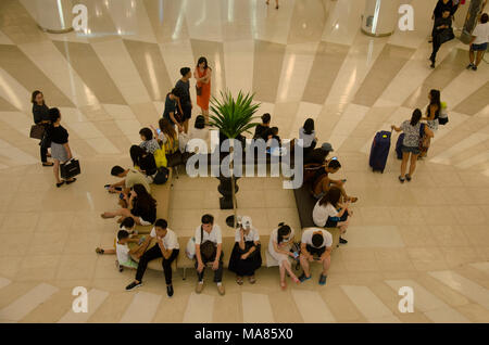 Persone sedute e attendere al punto di incontro e di gente che passeggia e usare escalator per muovere in su e in giù per lo shopping al department store in maggio 23, 2017 Foto Stock