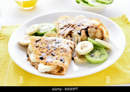 Crepes con banana, fette di kiwi e salsa al cioccolato. Vista ravvicinata Foto Stock