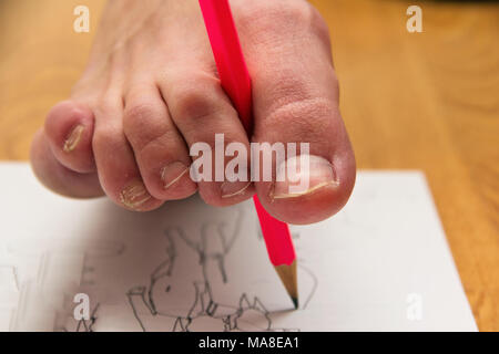 Una donna dipinge un quadro con una matita incolore con un dito del piede. Foto Stock