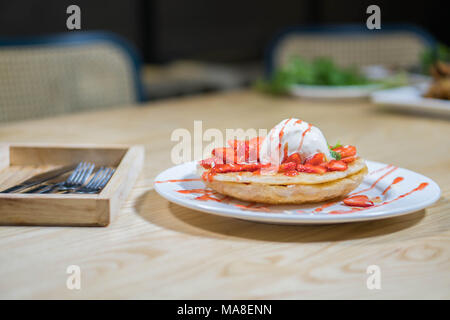 Toast con gelato e fragole fresche con panna montata sulla piastra bianca Foto Stock