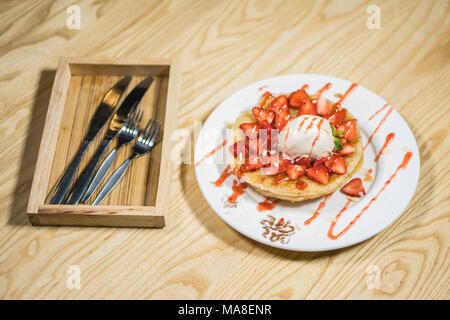 Toast con gelato e fragole fresche con panna montata sulla piastra bianca Foto Stock