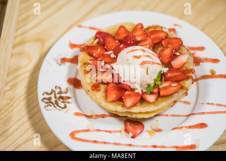 Toast con gelato e fragole fresche con panna montata sulla piastra bianca Foto Stock