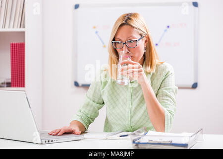 Imprenditrice sta lavorando nel suo ufficio. Ella è acqua potabile. Foto Stock