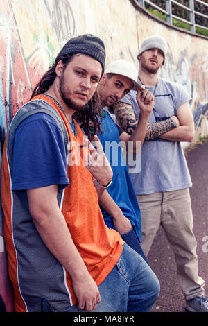 Tre cantanti rap in una metropolitana con graffiti in background in posa di stile aggressivo Foto Stock