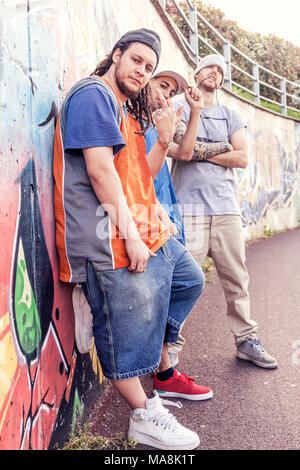 Tre cantanti rap in una metropolitana con graffiti in background in posa di stile aggressivo Foto Stock