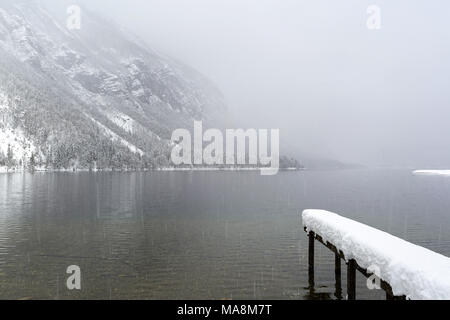 Una coperta di neve dock e le montagne circostanti il lago di Bohinj Foto Stock