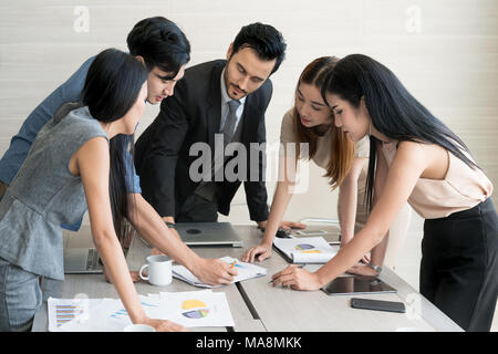 Smart manager spiegando riunione interna al suo team di progetto in un ufficio moderno. La multi etnico persona business group in tuta. Progetto e Business c Foto Stock