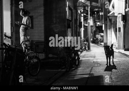 Un uomo si erge nei pressi di una porta a mangiare come cane si erge nelle vicinanze Foto Stock