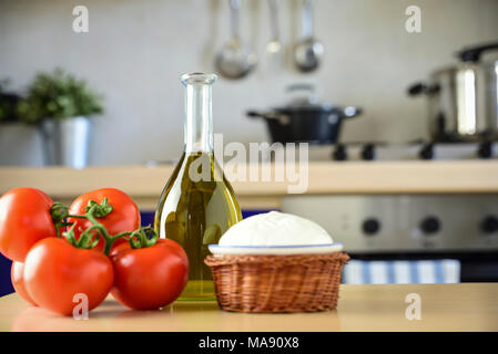 In cucina, sul tavolo, pomodori, mozzarella e olio. I prodotti tipici di una sana dieta mediterranea con cui il più classico della Ital Foto Stock