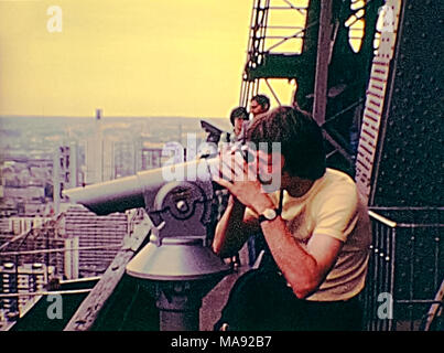 Parigi, Francia - circa 1976: Turisti in vintage 70s abito, guardando il panorama di Parigi dalla Torre Eiffel con il telescopio. Archivio Storico di riprese in Parigi città della Francia negli anni settanta. Foto Stock