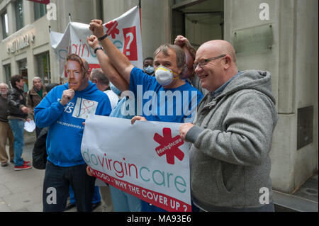 Manifestanti alzare i pugni fuori vergine Care HQ a Londra per chiedere la fine delle imprese private con il logo di NHS e per la Vergine a smettere di elusione fiscale. Foto Stock