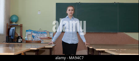 Insegnante in classe vicino alla scrivania. Foto Stock