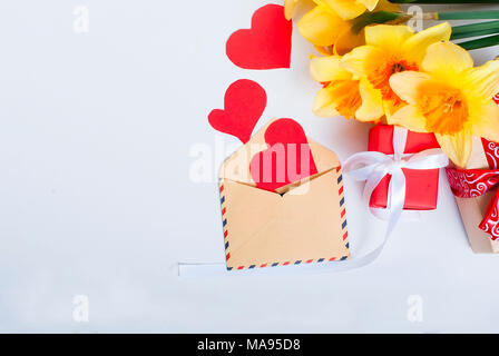 Vista superiore mazzo di narcisi e confezione regalo con nastro rosso su sfondo nero. Fiori il concetto di sfondo spazio copia Foto Stock