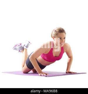 Giovane donna facendo spingere verso l'alto con le gambe incrociate a caviglia, studio shot. Foto Stock