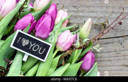 Bouquet con rosa e viola tulipani e piccola lavagna con il testo: ti amo Foto Stock
