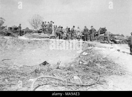 Fotografia in bianco e nero che mostra un grande gruppo di uniformata di soldati USA e due donne in abiti civili, in piedi di fronte a un muro di sacchi di sabbia, con un paesaggio roccioso in primo piano, fotografato in Vietnam durante la Guerra del Vietnam (1955-1975), 1971. () Foto Stock