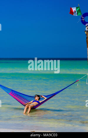 Donna rilassarsi in un'amaca sulla spiaggia di Holbox, Messico Foto Stock