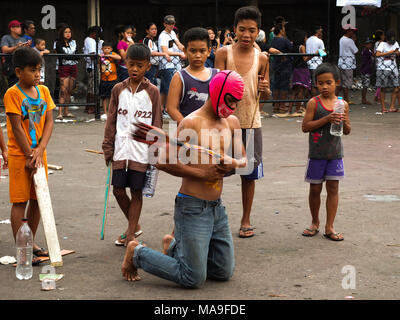 Marzo 28, 2012 - Navotas City, Filippine - un flagellant mantecato il suo retro, mentre i ragazzi guardano..il Venerdì Santo nelle Filippine sono costituiti da diversi riti come la flagellazione o facendo self infliggere una ferita per il corpo. Sfilando Gesù Cristo le repliche per riattivare la passione e le sofferenze di Gesù Cristo. (Credito Immagine: © Josefiel Rivera/SOPA immagini via ZUMA filo) Foto Stock