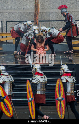 Londra, Regno Unito. Il 30 marzo, 2018.Gesù viene portato giù dalla croce - Wintershall giocatori open-air rievocazione della 'La Passione di Gesù " il Venerdì Santo sotto la pioggia in Trafalgar Square. È caratterizzato da un cast di oltre cento volontari di in ed intorno a Londra. Credito: Guy Bell/Alamy Live News Foto Stock