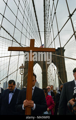 New York, NY, STATI UNITI D'AMERICA MARZO 30, 2018 Un giovane uomo porta una croce di legno attraverso il Ponte di Brooklyn, come parte di una processione del Venerdì Santo a New York Credito: James Kirkikis/Alamy Live News Foto Stock