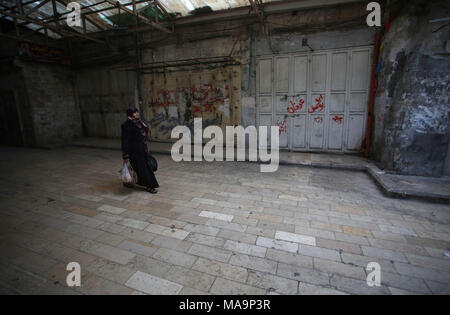 Nablus, West Bank, Palestina, 31 marzo 2018. Una donna Palestinese passeggiate passato negozi chiusi come Palestinesi osservare uno sciopero generale in solidarietà con la striscia di Gaza e la 15 palestinesi che sono stati uccisi ieri durante il grande ritorno a marzo si scontra in Cisgiordania città di Nablus, 31 marzo 2018. Foto: Ayman Nobani/dpa Foto Stock