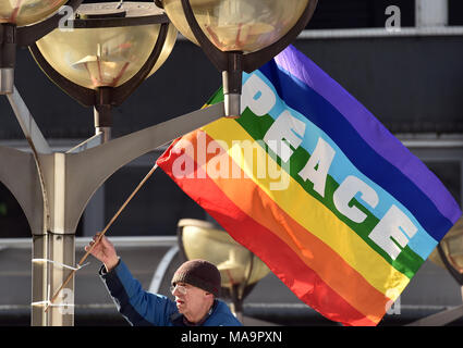Gronau, Germania. 31 Mar, 2018. Il 31 marzo 2018, Germania, Duisburg: Un partecipante sventola una bandiera della pace durante la Pasqua Rhine-Ruhr marzo per il disarmo. Credito: Caroline Seidel/dpa/Alamy Live News Foto Stock