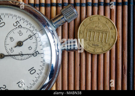 Monete in euro con una denominazione di 10 centesimi di euro e cronometro sul tavolo di legno - Lato posteriore Foto Stock