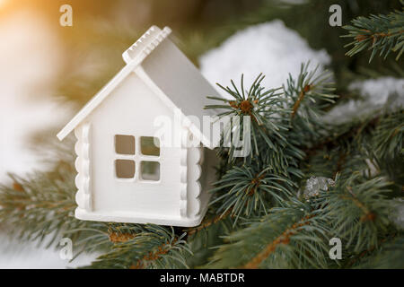 Miniatura white house si trova su un ramo di pino in inverno Foto Stock