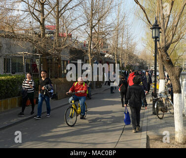 Occupato Hutong scena di strada con i ciclisti e i pedoni accanto a l'Houhai Lake nel nord centrale di Pechino, Cina Foto Stock