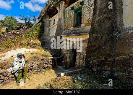 Pellegrino presso l'ingresso alla chiesa ortodossa di rock-conci di chiesa Medhane Alem Kesho, Tigray, Etiopia Foto Stock
