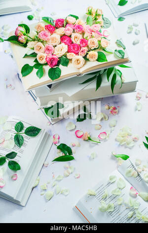 Molla di concetto di lettura. Pila di libri bianchi con fiori e petali di fiori. Femminile di vita ancora in alta chiave con copia spazio. Foto Stock