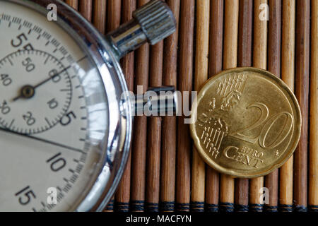 Cronometro e moneta con un valore nominale unitario di venti centesimi di euro sul tavolo di legno sfondo Foto Stock