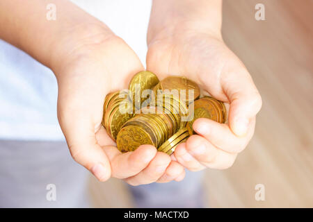 Un mazzetto di piccole monete nelle mani di un ragazzino. Bambino di risparmio di denaro.il denaro dalla Repubblica ceca. Foto Stock