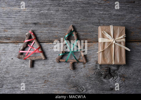 Due ramoscello di alberi di Natale e un tipo di carta presente avvolto su una tavola in legno rustico. Foto Stock