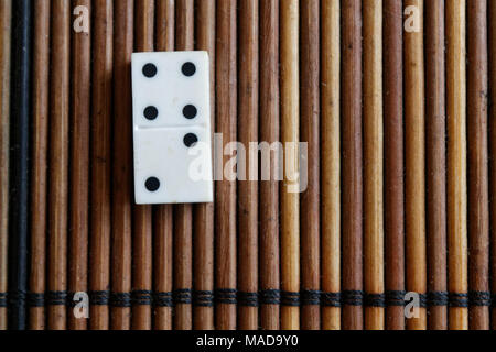 Pezzo di Domino sul bambù in legno marrone sfondo tabella. Set di Domino - due - 4 punti. Foto Stock