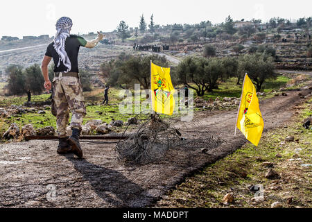 Bilin, Palestina, Dicembre 31, 2010: palestinese giovane con una pace della recinzione tagliata e Fatah flags è rivolta IDF squad (in background). Il fenc Foto Stock