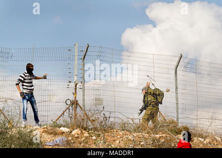 Bilin, Palestina, 1 Gennaio 2011: gioventù palestinese hits soldato israeliano con pietre in Bilin durante la dimostrazione contro la presenza israeliana a ovest Foto Stock