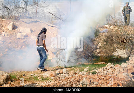 Bilin, Palestina, 1 Gennaio 2011: palestinese è la visione di gas lacrimogeni in uscita della granata durante la dimostrazione contro la presenza israeliana in Cisgiordania. Foto Stock