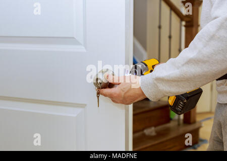 Installare il meccanismo di chiusura sportello e l'hardware. Le mani la riparazione di una serratura della porta con un cacciavite Foto Stock