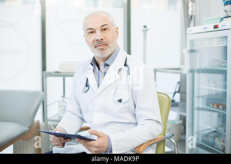 Fiducioso coppia medico in uniforme seduto in poltrona mentre si lavora con documenti in cliniche Foto Stock