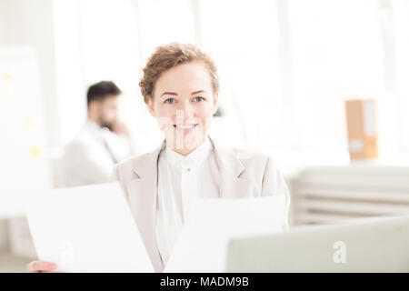 Ritratto di sorridere imprenditrice avente una documentazione in ufficio Foto Stock