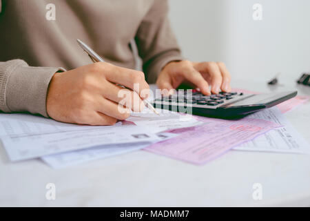 Man mano facendo finanze e calcolare sulla scrivania su costo presso l'ufficio domestico. Foto Stock