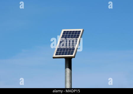 Piccolo pannello solare montato in alto sulla cima di uno spessore di metallo grigio sul polo caldo e soleggiato giornata invernale con cielo blu chiaro in background Foto Stock