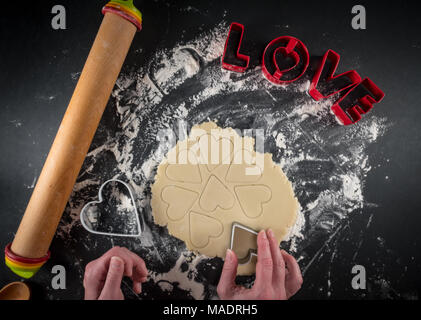 Mani Cuori di taglio in pasta biscotto su sfondo nero Foto Stock