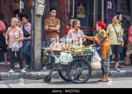 Donna l'acquisto di riso appiccicoso da un venditore ambulante, Chinatown, Bangkok, Thailandia Foto Stock