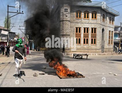 Srinagar, India. 1 apr, 2018. Un Kashmir protester sorge accanto bruciando pneumatici durante una manifestazione di protesta a Srinagar, Indiano Kashmir amministrato. Otto militanti sospetti e 2 indiano esercito di uomini sono stati uccisi in incontri separati nel sud del Kashmir. Due civili sono stati anche uccisi e decine di altri feriti negli scontri scoppiati tra i manifestanti e forze di sicurezza seguenti tre incontri separati in diverse parti del Kashmir. I separatisti hanno chiamato per una chiusura il lunedì contro le uccisioni. Credito: Saqib Majeed SOPA/images/ZUMA filo/Alamy Live News Foto Stock