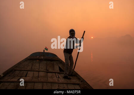 Uomo locale spostando barca sul fiume Yamuna con un palo di sunrise, Agra, Uttar Pradesh, India. Agra è una delle più popolose città in Uttar Pradesh Foto Stock