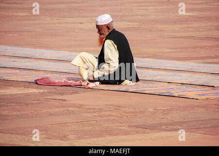 Local uomo seduto nel cortile della Jama Masjid in Fatehpur Sikri, Uttar Pradesh, India. La moschea è stata costruita nel 1648 dall'imperatore Shah Jahan e dedi Foto Stock